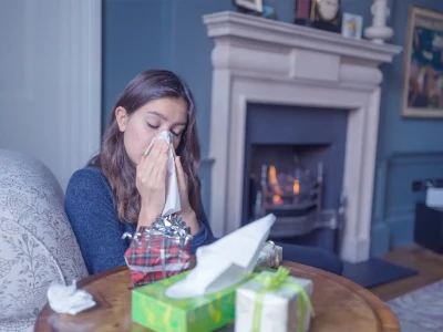 Kobieta siedząca w łóżku między zużytymi chusteczkami, dmucha nos