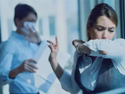 Kobiety w biurze kaszlące w łokieć i w chusteczkę